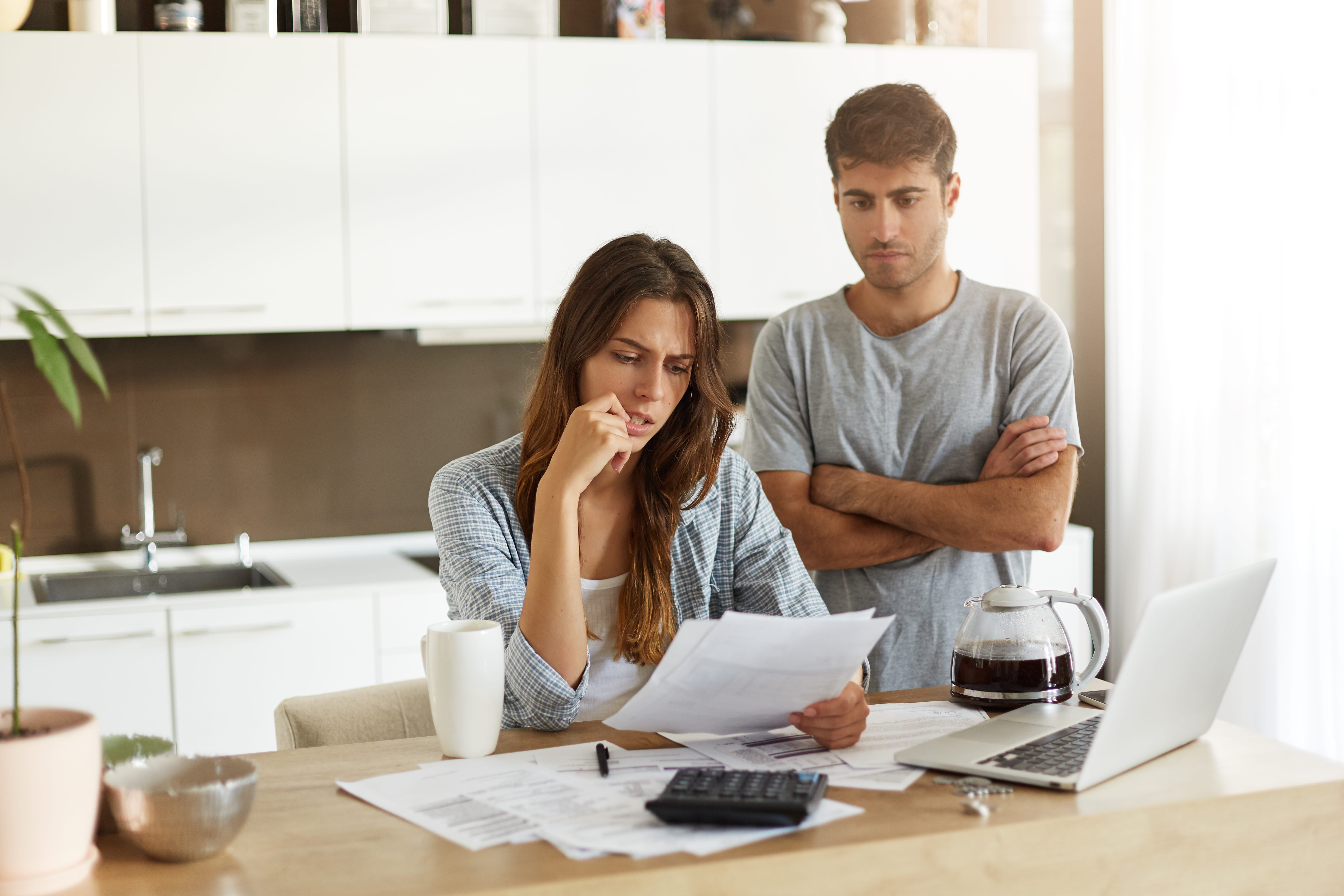 candid-shot-young-american-man-woman-dressed-casually-feeling-stressed-while-managing-finances-kitchen-together-calculating-expenses-paying-utility-bills-online-laptop-computer